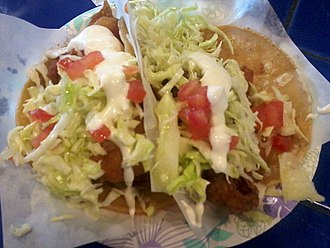 Two fried fish tacos in hard tortilla shells.